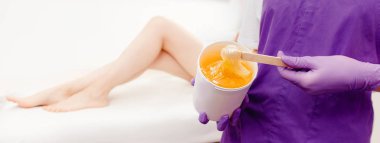 Women beautician holds jar of paste for sugar depilation shugaring, white background clipart