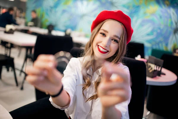 Jeune belle France fille dans un béret rouge dans un café montre des lunettes. Concept de santé dentaire et oculaire — Photo