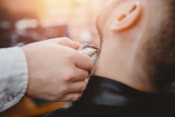 Barbiere che tagliano barba a uomo in barbiere che incorniciano l'attaccatura dei capelli. rasoio elettrico, marrone scuro vintage — Foto Stock