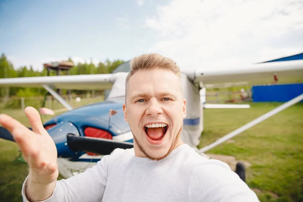 Pilot robi sobie selfie na planie tła, uśmiechając się szczęśliwie — Zdjęcie stockowe