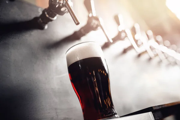 Dark Draft koud bier giet glas van kraan in pub — Stockfoto