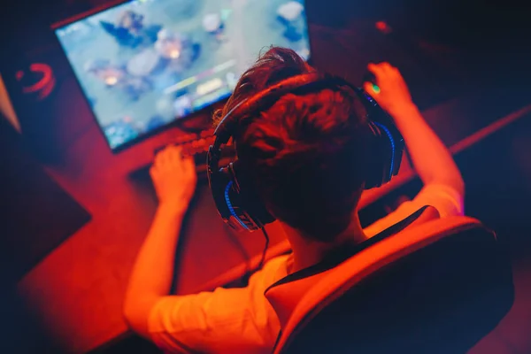 Videojuego profesional jugando torneos de juegos en línea ordenador PC con auriculares, fondo rojo y azul borroso — Foto de Stock