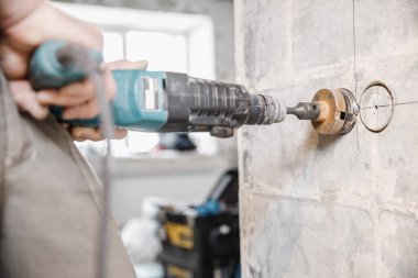 Elektrik prizi için çekiç matkaplarıyla duvarda sıkıcı bir delik