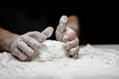 El fırıncısı hamur mayasını siyah arka planda beyaz toz unuyla hazırlıyor. Makarna ve pizza için kepçe.