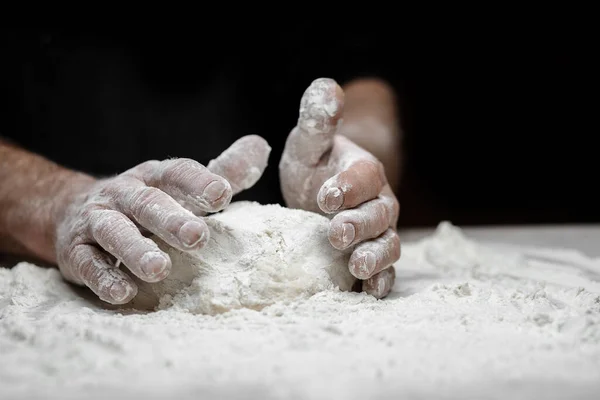 Tukang roti tangan menyiapkan adonan khamir dengan tepung debu putih dengan latar belakang hitam, sendok pasta dan pizza — Stok Foto