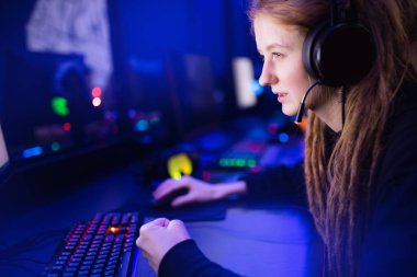 Streamer güzel kız profesyonel oyuncu gülümsemesi çevrimiçi oyunlar oynuyor kulaklıkla bilgisayar, neon rengi