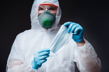 Medic man in white hazmat protective holding gauze bandage mask for respiratory diseases pneumonia epidemic coronavirus