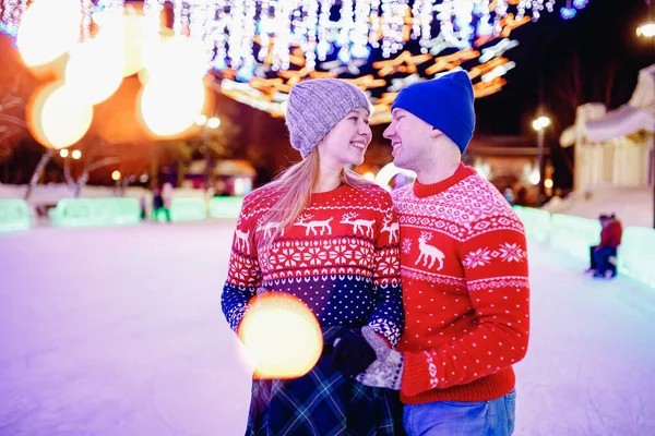 Happy young couple in sunny winter nature ice skating night illumination — Stock Photo, Image