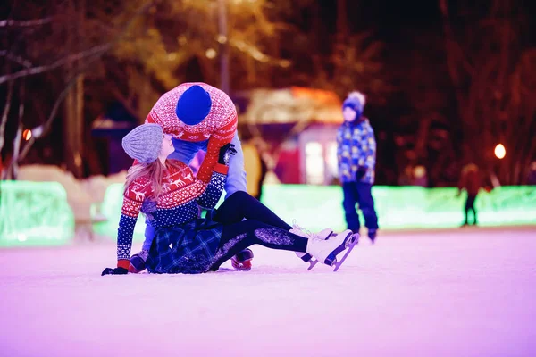 Cara jovem se familiariza com a menina no inverno rinque em patins de gelo, conceito primeira noite iluminação amor — Fotografia de Stock