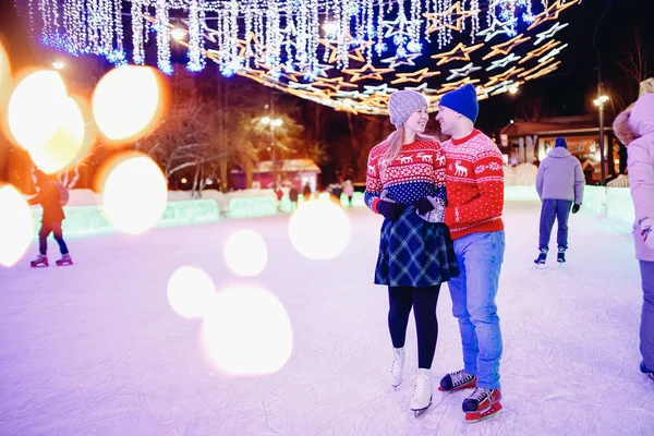 Pattini invernali, coppia amorevole che si tiene per mano e rotola sulla pista di pattinaggio. Concetto formazione illuminazione notturna — Foto Stock