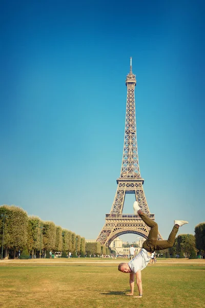 Young male tourist on field in front of Eiffel Tower Paris makes photo, France