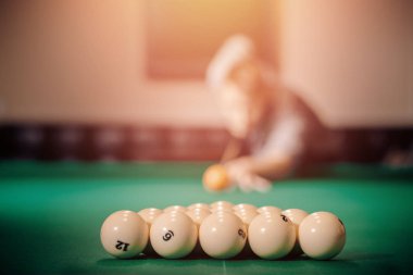 Man is player preparing and aiming to smash white balls in Russian billiards on green table