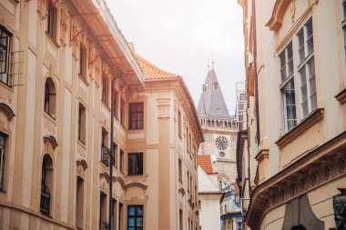 European street, houses with red tiled roofs, leads to Gothic clock tower