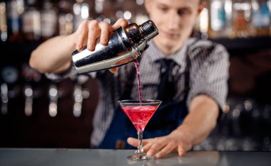Barman alkol ve buz ile shaker kokteyl hazırlar. Koyu arka plan Barmen