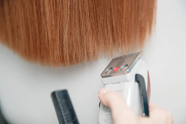 Резка рыжих волос с клиппером на белом фоне — стоковое фото