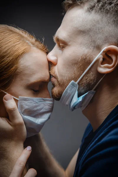 Lover man and girl kiss in protective masks respirator on dark background, people affected epidemic virus, spread airborne droplets
