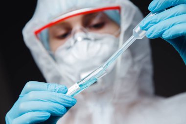 Beyaz tehlikeli madde koruma araştırma görevlisi modern laboratuvarda kan testi yapıyor. Mavi renk, korona virüsü salgını