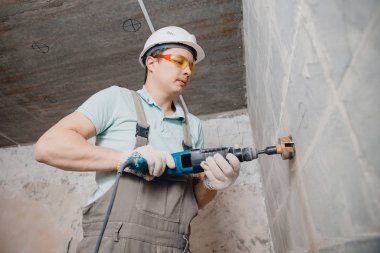 İnşaatçı işçi pnömatik çekiç delme delikleri beton tuğla duvar ve elektrik kablosu için elmas taç, soket, anahtar