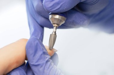 Master removes shellac gel from woman nails salon, manicurist use portable pen shape electric drill manicure