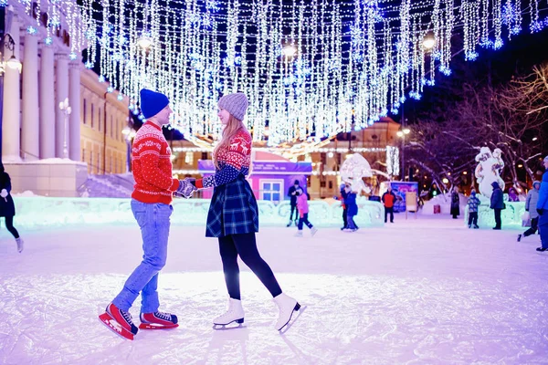Felice giovane coppia in soleggiato inverno natura pattinaggio sul ghiaccio notte illuminazione — Foto Stock