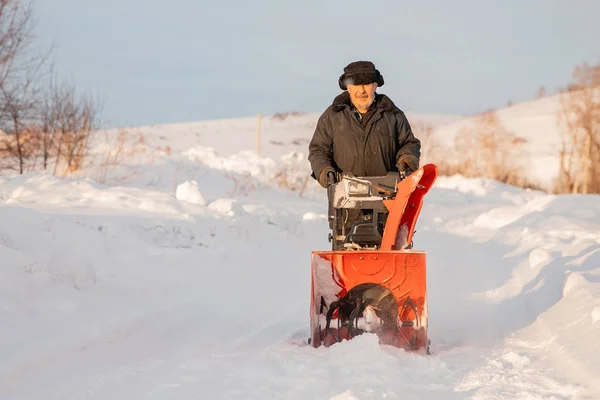 Człowiek czyszczący śnieg z chodników za pomocą maszyny do odśnieżania zimą — Zdjęcie stockowe