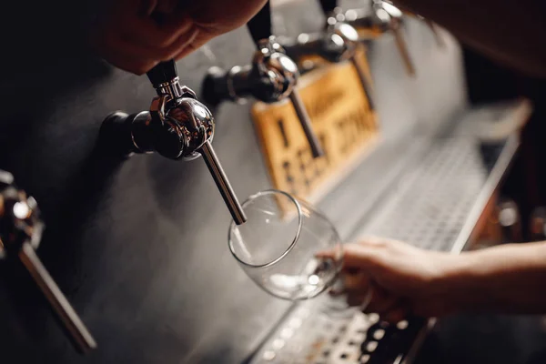 Il barman versa il sidro alcolico leggero di barilotto nel bicchiere. Sfondo scuro — Foto Stock