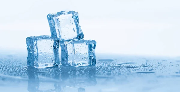 Cubos de hielo cuadrados con gotas de agua limpia sobre fondo azul —  Fotos de Stock