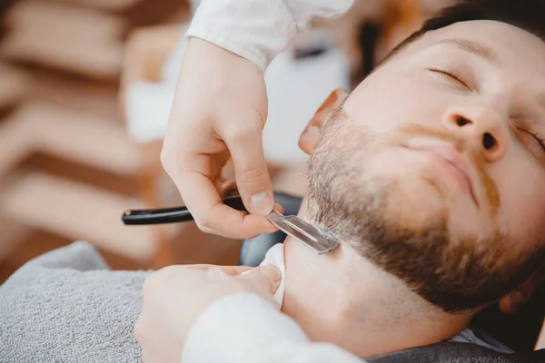 Man met baard klant in kapsalon kapper op scheren met gevaarlijke scheermes — Stockfoto