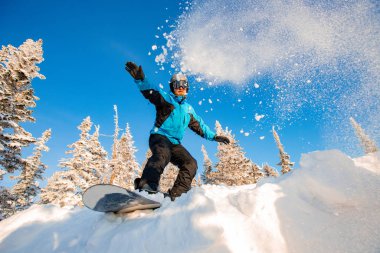 Snowboard sporcusu ormanda taze kar üzerinde geziyor, toz patlaması