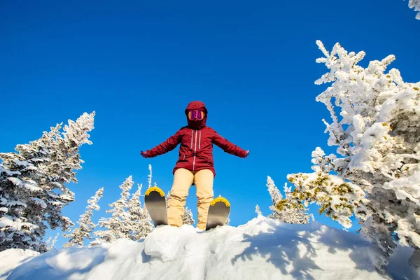 Giovane donna salto con gli sci dal trampolino di lancio nella foresta innevata fuori pista, concetto di sport estremi invernali — Foto Stock