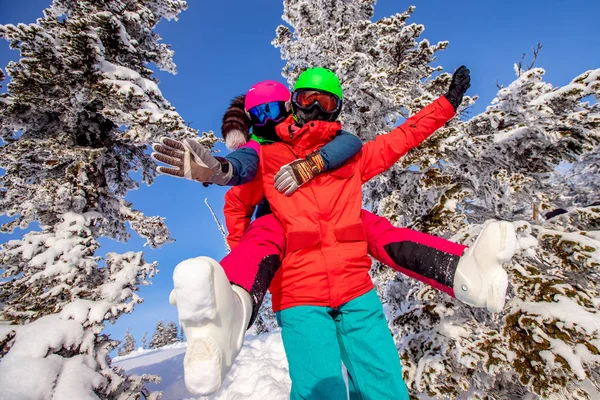 Snowboarder uomo e donna sciatore abbracciare e divertirsi sullo sfondo della foresta invernale e neve. Luce del sole in montagna — Foto Stock