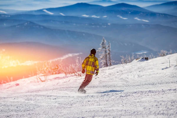 Snowboarder sullo sfondo della stazione sciistica, vista posteriore, alta montagna, giornata di sole — Foto Stock