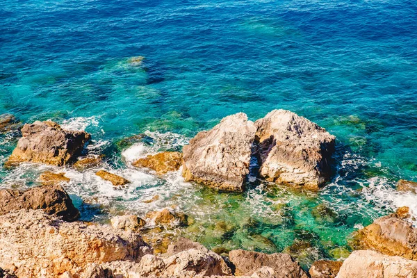 Achtergrond natuurlijke mooie turquoise zeewater met rotsen en rotsachtige strand, transparante bodem — Stockfoto