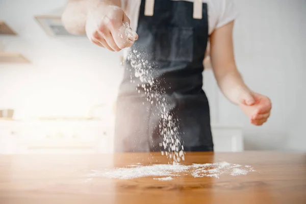 Chef cospargere di farina bianca con mano uomo polvere su pasta fresca, sfondo chiaro — Foto Stock