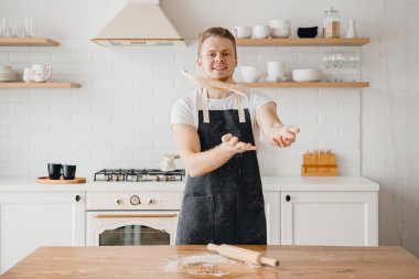 Pizza üreticisi önlüklü aşçı mutfak arka planına hamur atıyor.