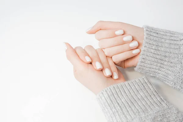 Manicure elegante em mulher jovem em unhas, cor rosa claro, fundo branco — Fotografia de Stock