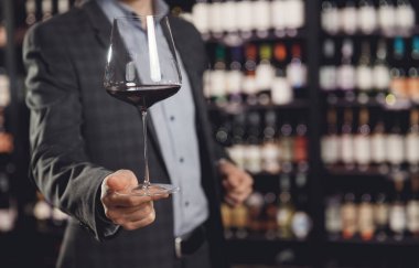 Garson restoranda bir bardak kırmızı şarap servis ediyor.