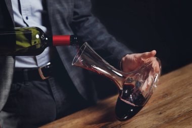 Sommelier erkeği tat ve aromanın havalanması için sürahiye kırmızı şarap doldurur.