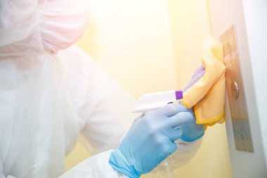 Coronavirüs dezenfeksiyonu. Tehlikeli maddeler kullanan insanlar asansör dairesinde temizlik yapıyorlar.