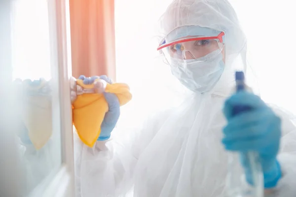 Απολύμανση και καθαρισμός χειρολαβών πόρτας του σπιτιού από μόλυνση με ιό και μικρόβια σε βιοχημική στολή. Έννοια προστασίας από τον ιό Coronavirus — Φωτογραφία Αρχείου