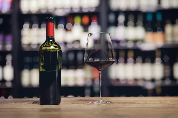 Copo e garrafa de vinho tinto no balcão de madeira bar no restaurante, espaço de cópia — Fotografia de Stock