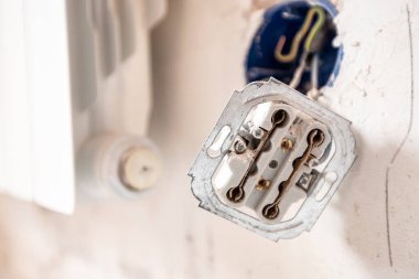 Patlama duvarındaki parçalanmış elektrik prizi. Dairenin tamiri sırasında çıplak kablolar ve işaretlerle.