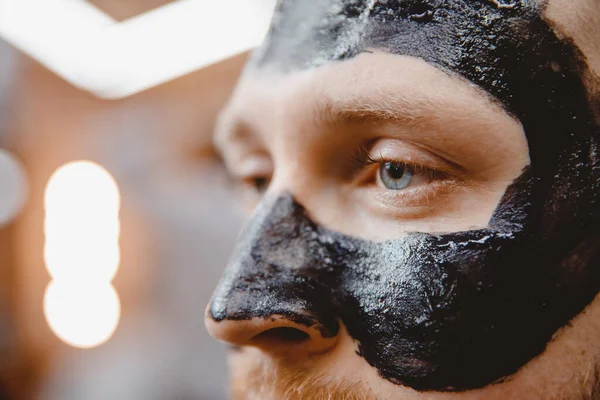 Bel homme avec masque noir charbon de bois, concept soins de la peau, nettoyage des pores de l'acné — Photo