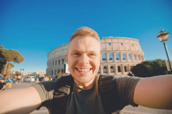 Χαρούμενος νεαρός που βγάζει σέλφι μπροστά από το Κολοσσαίο στη Ρώμη, στην Ιταλία. Έννοια ταξίδι — Φωτογραφία Αρχείου