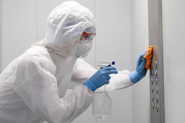 Coronavirüs dezenfeksiyonu. Tehlikeli maddeler kullanan insanlar asansör dairesinde temizlik yapıyorlar.