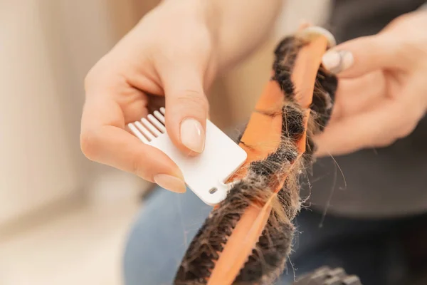 Donna pulisce spazzola da animale domestico capelli e detriti da robot automatico aspirapolvere — Foto Stock