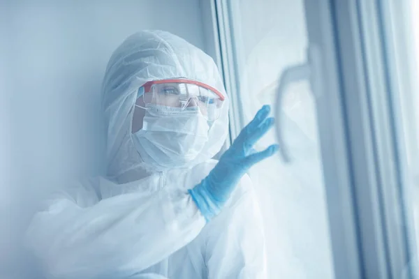 Cuarentena de soledad, mujer joven con máscara médica mira por la ventana de auto aislamiento. Concepto pandémico del Coronavirus —  Fotos de Stock