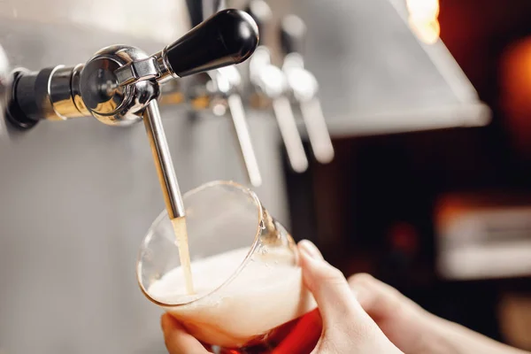 Il barista versa la birra dal rubinetto al bicchiere, sfondo scuro. Alcol mestiere bevanda concetto — Foto Stock
