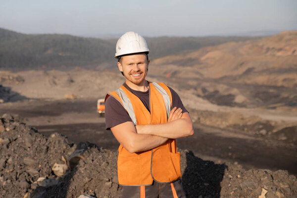 Engineer smiling man in white helmet on background open pit mine industry