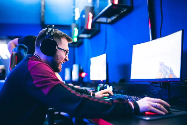 Giocatore professionista che gioca tornei di videogiochi online computer con cuffie, rosso e blu — Foto Stock